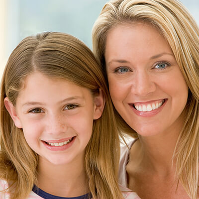 A girl next to her mom smiling in front