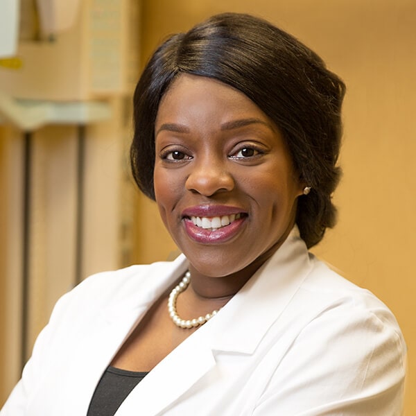Dr. Ngozi Okoh smiling while wearing a pearl necklace and her dentist coat