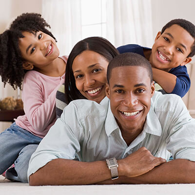 A family of four lying on the floor in the living room while smiling