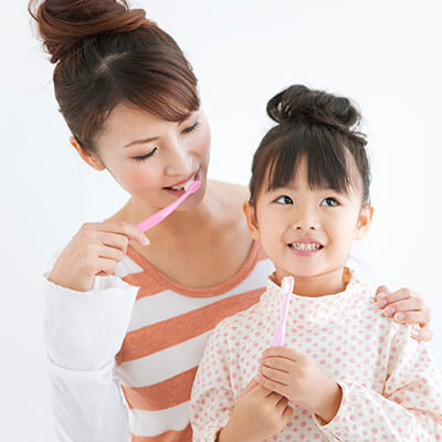 A mother teaching her little daughter how to brush her teeth