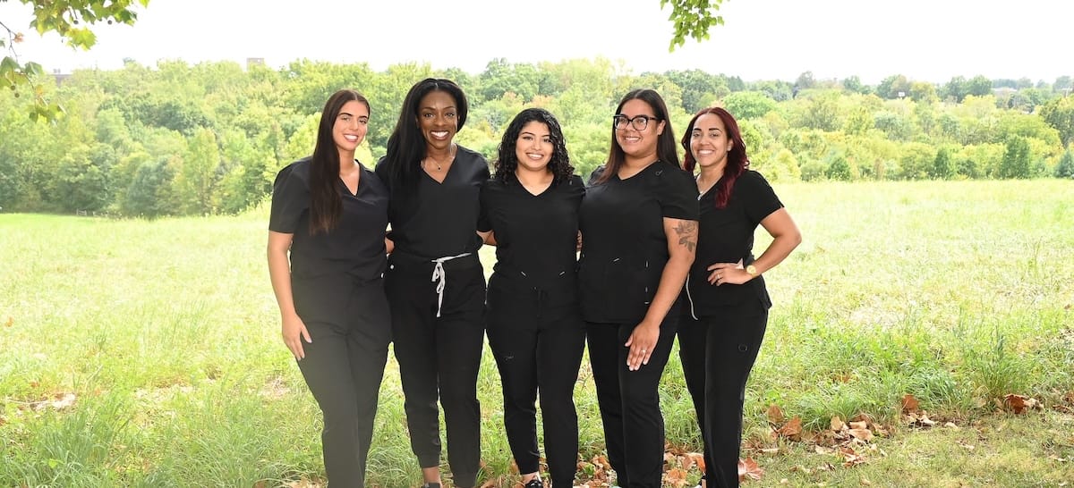 Dr. Ngozi Okoh smiling while standing outside the dental office while wearing a pearl necklace